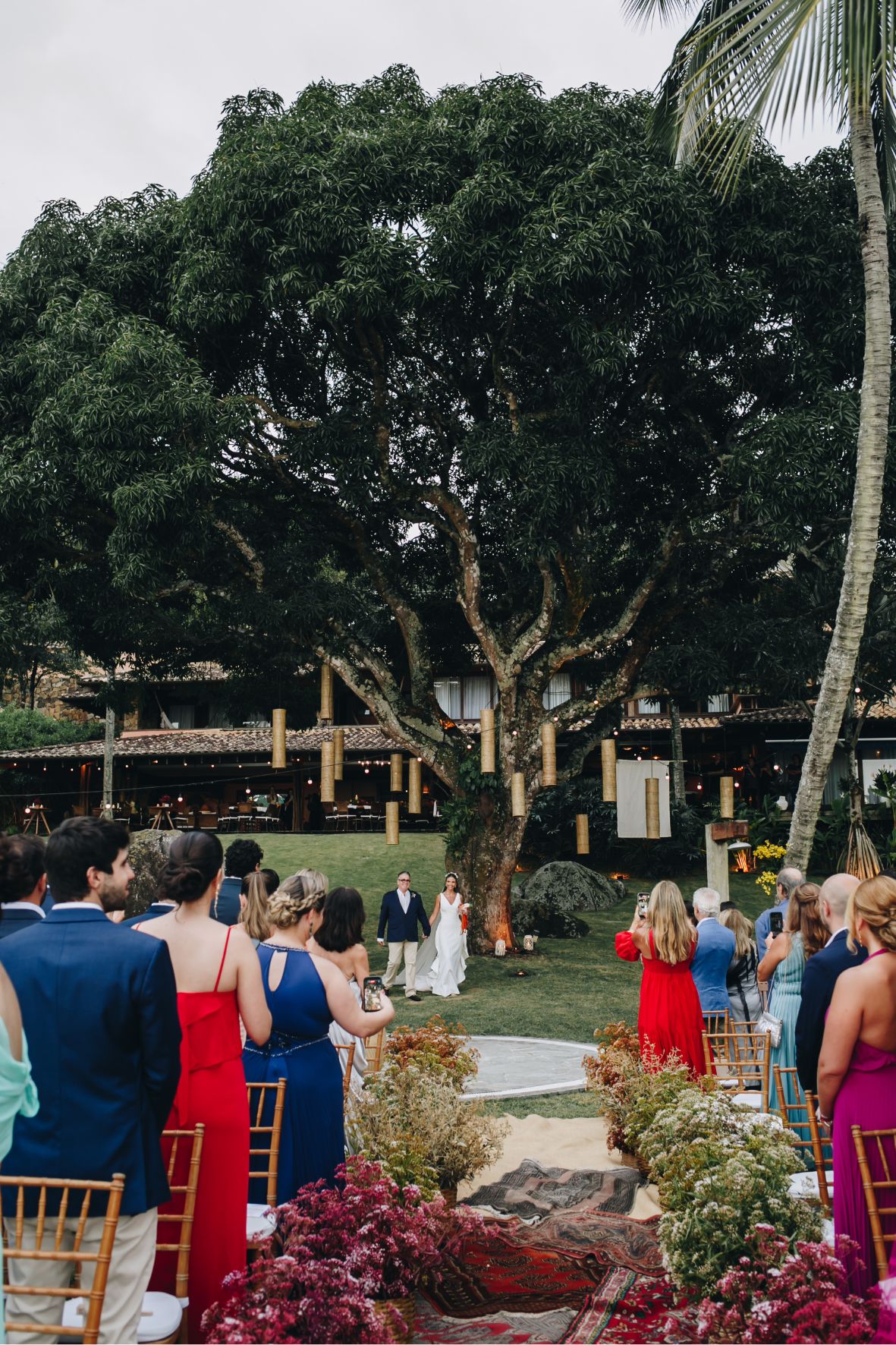 Luiza entrando com o pai no casamento à beira-mar em Ilhabela