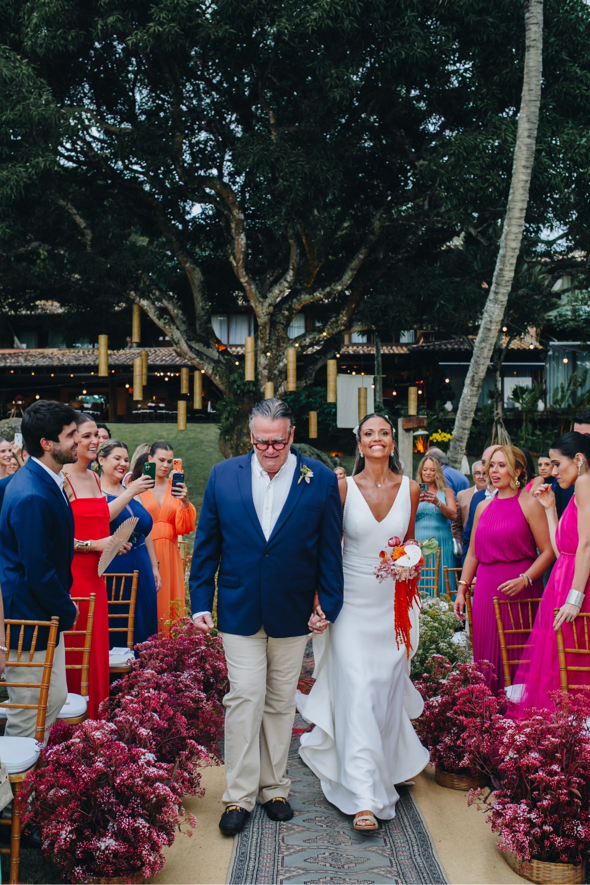 Luiza entrando com o pai no casamento à beira-mar em Ilhabela